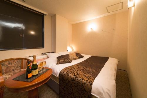um quarto de hotel com uma cama e uma mesa com garrafas de vinho em HOTEL le ROSEY em Kitakyushu