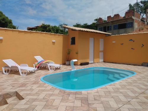 un patio con piscina, sedie e una casa di Orange House ad Araruama