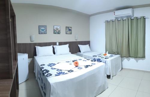 a bedroom with two beds and two tables in it at Pousada Gamela do Maragogi in Maragogi