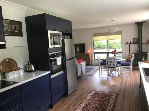 a kitchen with blue cabinets and a living room at Kymmik Cottage in Geeveston