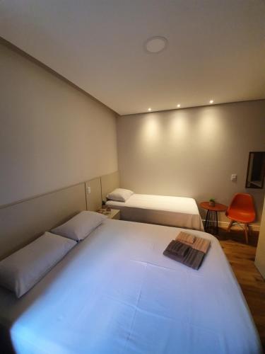 a bedroom with two beds and a red chair at Hotel do Parque - Cunha in Cunha