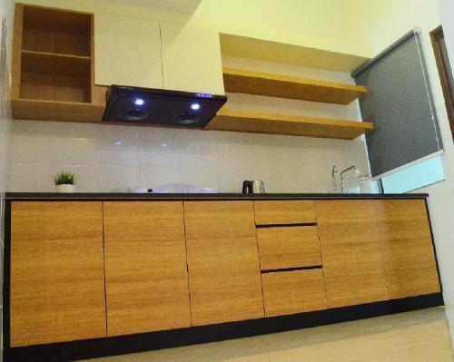 a kitchen with wooden cabinets and a black counter top at Desaru Cosy Homestay - near WaterPark, Beach, Rapid -Wifi, TVbox, Steamboat, BBQ Available in Desaru