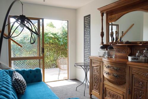 a living room with a blue couch and a wooden dresser at The Loft Matua in Tauranga