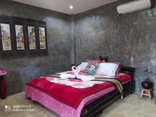 - une chambre avec un lit et une couverture rouge dans l'établissement Angels Chambres d'hotes, à Rong Sak
