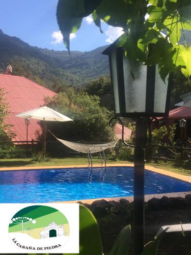 a swimming pool with a lamp next to a house at La Cabaña de Piedra in Las Trancas
