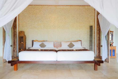 a bedroom with a white bed with a wall at The Bejalin Eco Retreat in Plaga