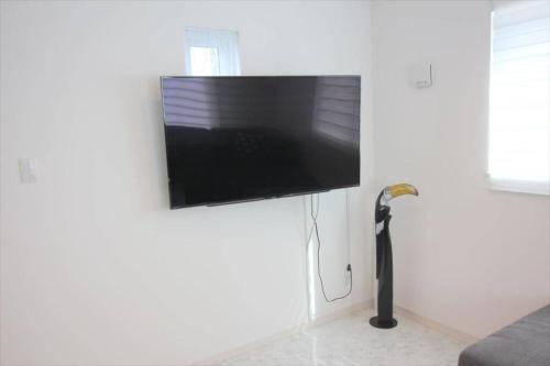 a flat screen tv hanging on a white wall at Casa de nicki 恩納村 in Onna
