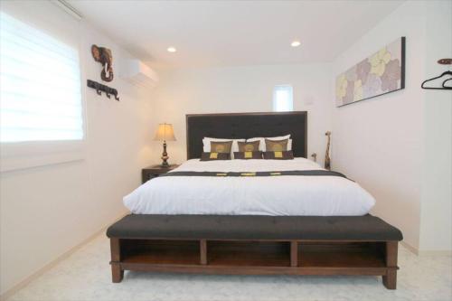 a white bedroom with a large bed with a black headboard at Casa de nicki 恩納村 in Onna
