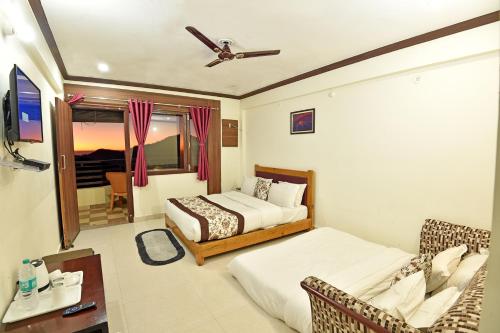 a hotel room with two beds and a tv at Green Roof Hotel in Nainital
