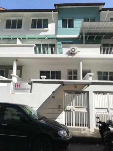 a black car parked in front of a white building at Island Hostel Bayan Lepas Airport in Bayan Lepas