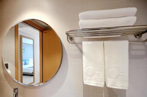 a bathroom with a mirror and towels on a rack at Sun Kiss Hotel in Nha Trang