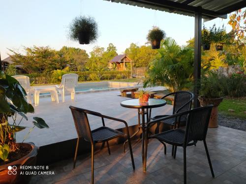 a patio with a table and chairs and a pool at Angels Chambres d'hotes in Rong Sak