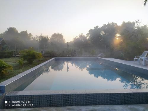 a swimming pool in a backyard with the sun setting at Angels Chambres d'hotes in Rong Sak