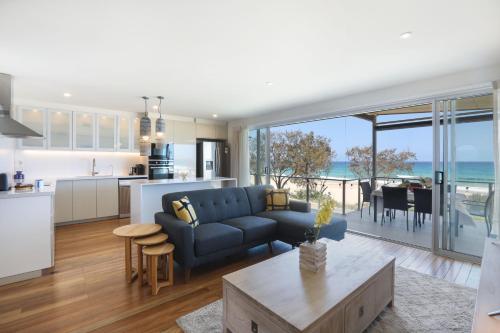 a kitchen and a living room with a blue couch and a table at Sandbox Apartments in Gold Coast