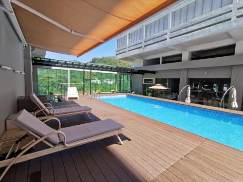 - une piscine avec 2 chaises longues à côté d'un bâtiment dans l'établissement Hotel Langkasuka Langkawi, à Kuah