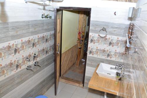 a bathroom with a shower with a sink and a mirror at Astraal Resorts and Spa in Rishīkesh