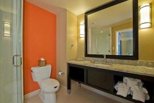 a bathroom with a toilet and a sink and a mirror at Hotel Indigo Atlanta Airport College Park, an IHG Hotel in Atlanta