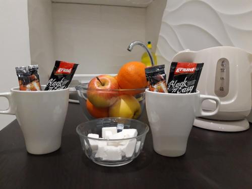 Un mostrador con dos tazas de café y un bol de fruta. en Apartmani Krtolica, en Novi Sad
