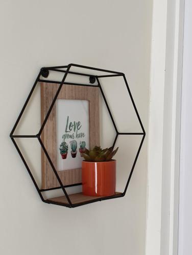 a black hexagon mirror with a potted plant on a wall at Villa B9us Batu in Karangploso
