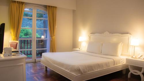 a bedroom with a white bed and a window at Colmar Tropicale in Bukit Tinggi