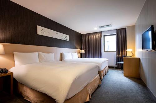 a hotel room with two beds and a television at Beacon Hotel in Taichung