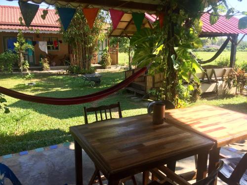 a wooden table in a yard with a hammock at Soluna Guest House in Pantai Cenang