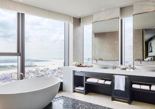 a bathroom with two sinks and a tub and a large window at Rosewood Phnom Penh in Phnom Penh