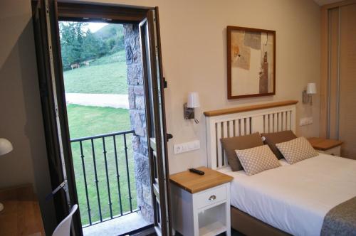 - une chambre avec un lit et une porte donnant sur un balcon dans l'établissement Apartamentos Rurales Peñon Blanco, à Peñerudes