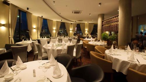 a restaurant with tables and chairs with white table cloth at Almond Hotel Bassac River in Phnom Penh