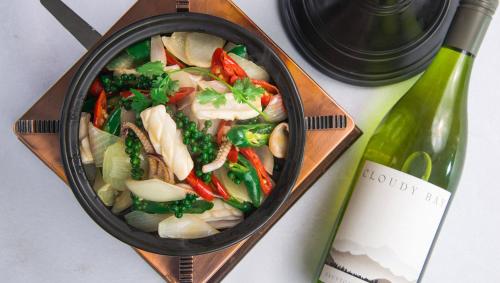 a pan filled with food next to a bottle of wine at Almond Hotel Bassac River in Phnom Penh