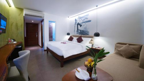 a bedroom with a bed and a couch and a table at Almond Hotel Bassac River in Phnom Penh