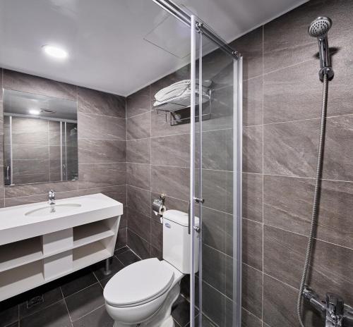 a bathroom with a toilet and a glass shower at Kenting City Gate Hotel in Hengchun
