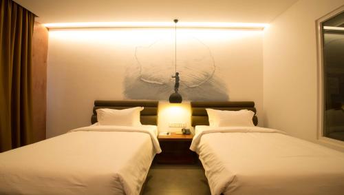 two beds in a room with a light between them at Almond Hotel Bassac River in Phnom Penh