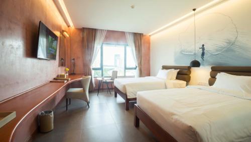 a hotel room with two beds and a desk at Almond Hotel Bassac River in Phnom Penh