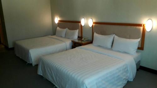 two beds in a hotel room with white sheets at Kenting City Gate Hotel in Hengchun