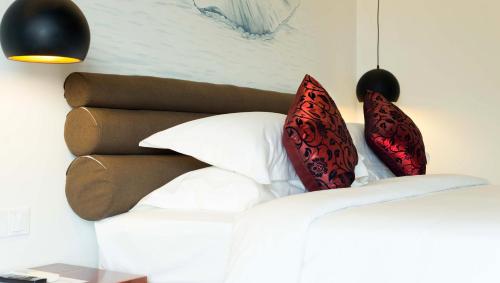 a bedroom with a bed with red pillows on it at Almond Hotel Bassac River in Phnom Penh
