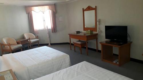 a hotel room with a bedroom with two beds and a mirror at Kenting City Gate Hotel in Hengchun