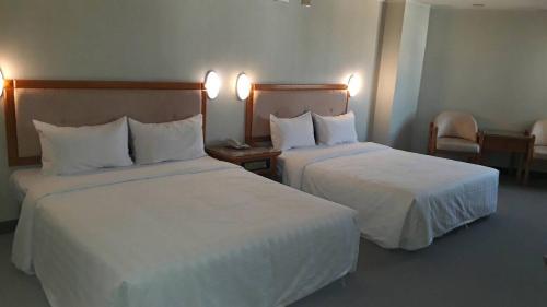 a hotel room with two beds with white sheets at Kenting City Gate Hotel in Hengchun
