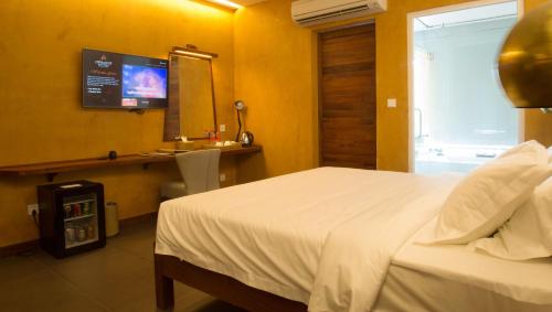 a bedroom with a bed and a sink and a television at Almond Hotel Bassac River in Phnom Penh