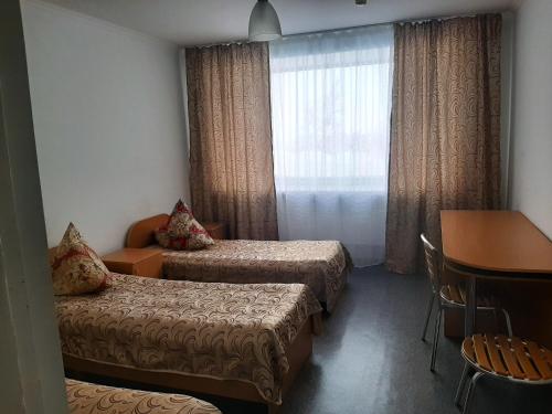 a room with two beds and a table and a window at Sanatoriy Zhosaly in Qarqaraly