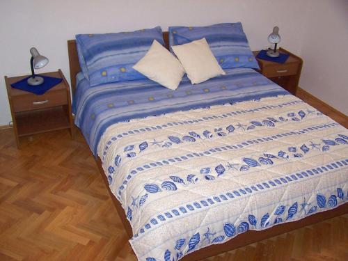 Cama con sábanas y almohadas azules y blancas en Seven Seas Apartments, en Mlini