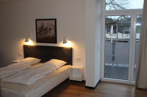 a bedroom with a bed and a large window at Dünenhaus Wohnung 6 in Lübeck