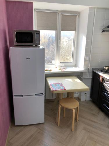 ジェレスノヴォツクにあるKarla Marksa Apartmentのキッチン(冷蔵庫、テーブル、電子レンジ付)