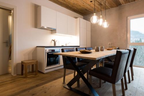 uma cozinha com uma mesa de jantar em madeira e cadeiras em WOO® Loft Resort em Fiesch