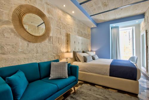 una camera con un divano blu e un letto di Barrakka Suites a La Valletta