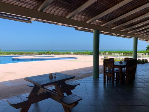 a table and chairs under a pavilion with a pool at Cimarron Suites Playa Parguito in Aricagua