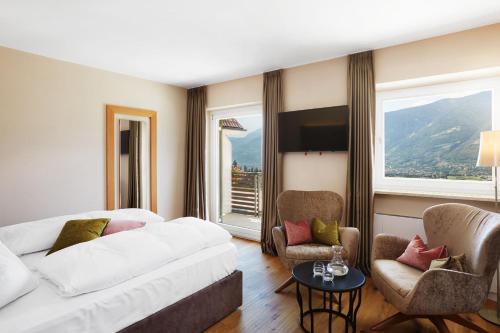 a hotel room with a bed and a couch and chairs at Hotel Mitterplatt (Schenna Resort) in Schenna