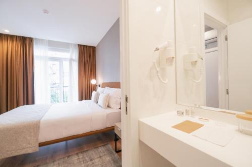 a bedroom with a bed and a sink and a mirror at LX SoHo Boutique Hotel by RIDAN Hotels in Lisbon