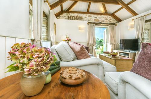 a living room with a table with flowers on it at Pear Tree Barn - Amazing Country views - Pet friendly - Balcony in Newquay