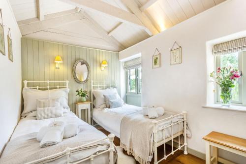 two beds in a room with white walls at Pear Tree Cottage in Newquay